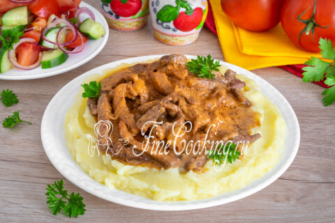 Бефстроганов из говядины в сковороде, готовый к подаче с гарниром.