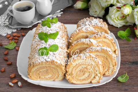 Нарезанный бисквитный рулет с вареной сгущенкой и арахисом на тарелке
