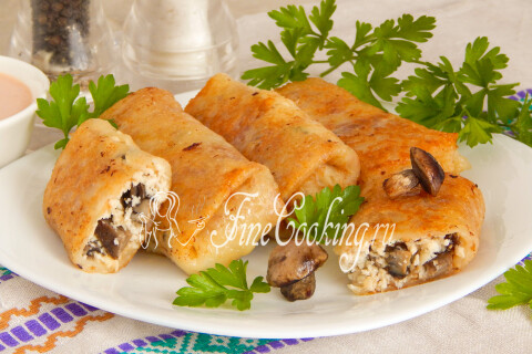 Блинчики с курицей и грибами на тарелке со сметаной и зеленью
