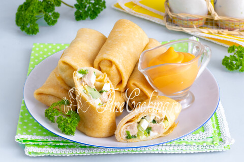 Заварные блинчики с печенью трески, яйцами, огурцом и зелёным луком на тарелке
