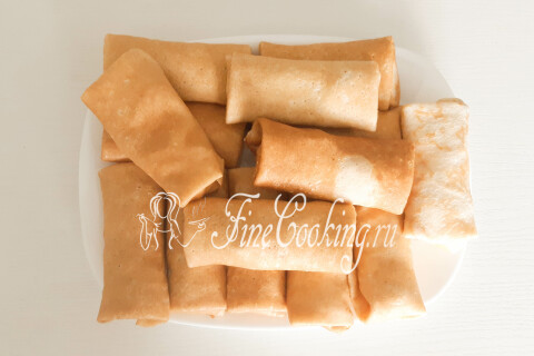 Готовые блинчики с творогом и клубникой, сложенные на тарелке