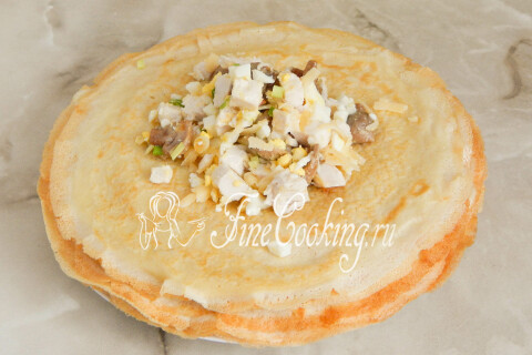 Ложка начинки на блинчике, разложенном на столе
