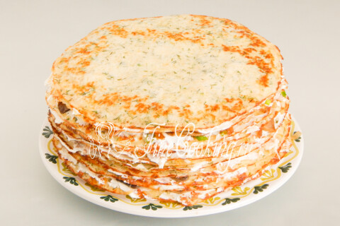 Готовый блинный торт с курицей и грибами на тарелке