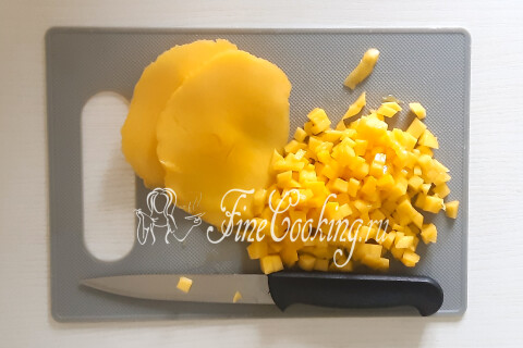 Манго, нарезанное мелким кубиком, на разделочной доске.