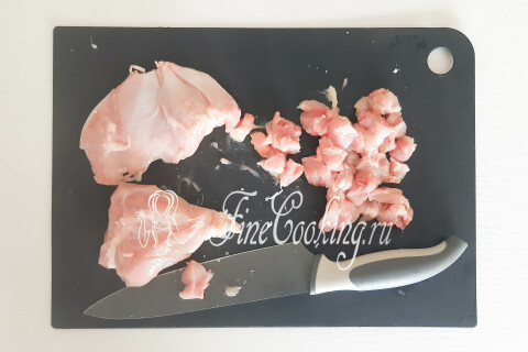 Филе курицы, нарезанное на разделочной доске небольшими кусочками для фарша