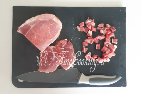 Подмороженная свинина, нарезанная мелкими кубиками на доске.