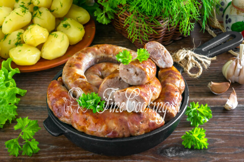 Сочная румяная домашняя колбаса из свинины в кишке, нарезанная кусочками на тарелке.
