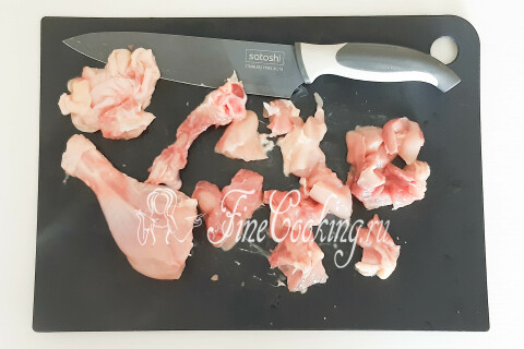 Куриное мясо, срезанное с тушки и нарезанное небольшими кусочками, на разделочной доске.