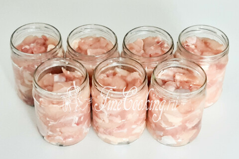 Семь наполненных куриным мясом баночек, выстроенных в ряд.