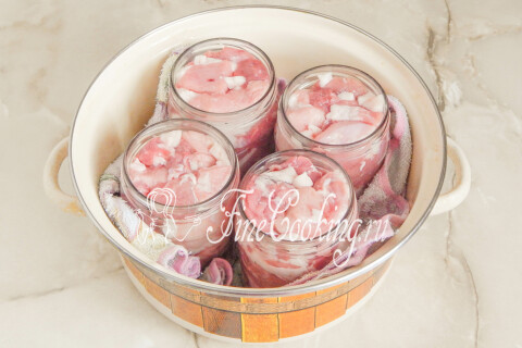 Банки с мясом на полотенце, постеленном на дно большой кастрюли