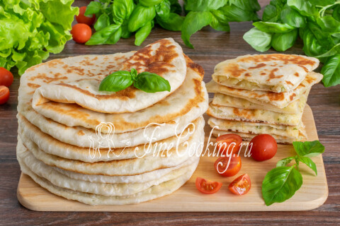 Готовые дрожжевые лепёшки с картошкой и луком на тарелке