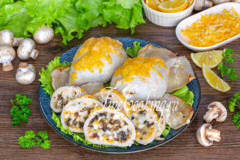 Фаршированные кальмары с грибами, сыром и яйцом, нарезанные тонкими ломтиками на тарелке.