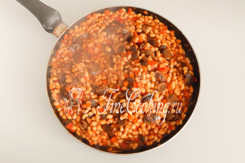 Готовая фасоль с грибами и овощами, посыпанная рубленой зеленью