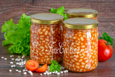 Фасоль в томатном соусе на тарелке рядом с мясной котлетой.