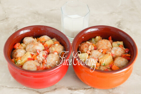 Мясные фрикадельки поверх картофеля в горшочках, залитые молоком.