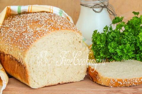 Нарезанный горчичный хлеб с кунжутной корочкой лежит на разделочной доске.