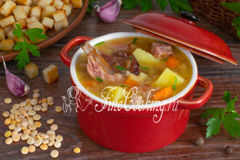 Дымящаяся тарелка супа с ложкой на столе рядом с гренками.