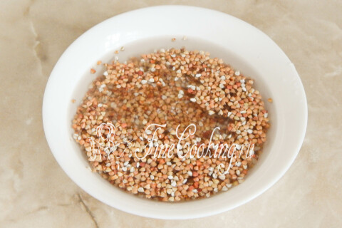 Промытая гречневая крупа стекает на сите после промывки водой.