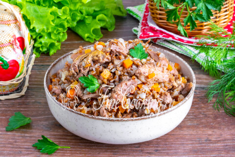 Рассыпчатая гречка с тушёнкой и овощами, поданная в тарелке горячей