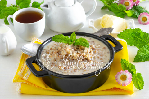 Молочная гречневая каша в тарелке, посыпанная кусочком сливочного масла.