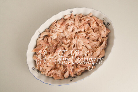 Разобранное куриное мясо, разложенное в глубокую керамическую форму
