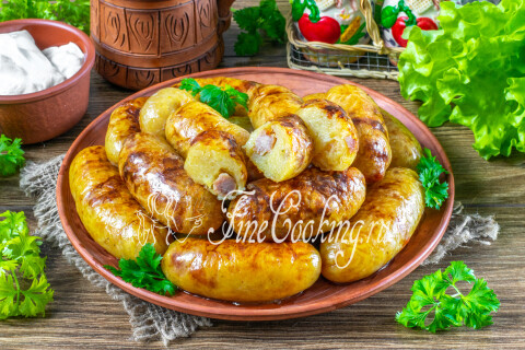 Готовая картофельная колбаса на тарелке с ложкой сметаны.