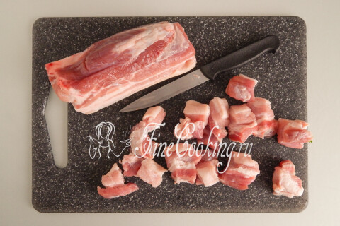 Свиная грудинка, нарезанная порционными кусочками на доске.