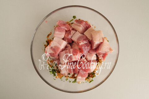 Кусочки свиной грудинки, добавленные к маринаду в миске.