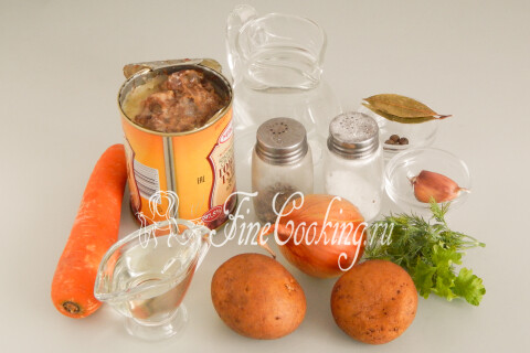Продукты для картошки с тушёнкой: картофель, тушёнка, репчатый лук, морковь, чеснок и зелень.