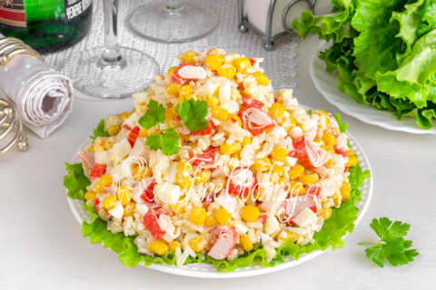 Салат с крабовыми палочками, кукурузой, яйцом и рисом в тарелке
