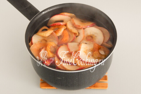 Кипящая жидкость с яблоками и изюмом на плите в течение нескольких минут.