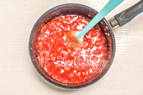 Прозрачная и глянцевая клубничная масса, загустевающая в кастрюле на плите.
