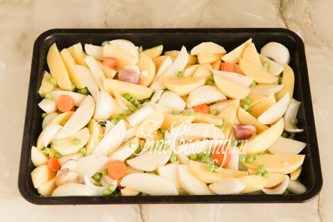 Противень с картофелем, морковью, луком и чесноком на дне духовки