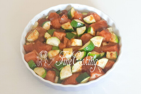 Кусочки маринованной курицы, разложенные между подрумяненными кабачками в форме.