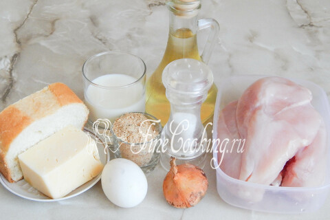 Куриная грудка, сыр, белый хлеб, молоко, яйцо и лук на столе