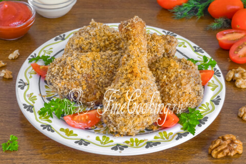 Готовые ножки в ореховой панировке на тарелке со свежими овощами и зеленью.