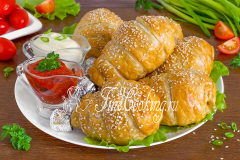 Румяные куриные ножки в слоёном тесте на тарелке с зеленью и соусом.