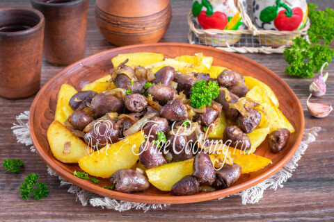 Куриные сердечки с луком на тарелке рядом с запечёнными дольками картофеля