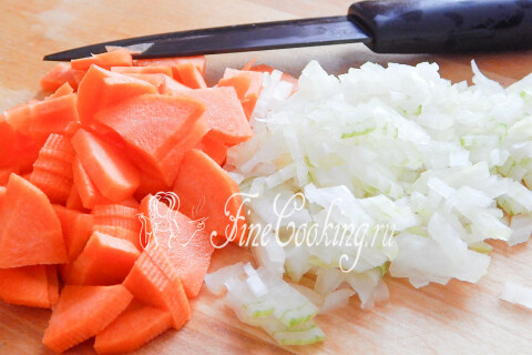 Куриный бульон на плите и измельчённые морковь с луком для супа