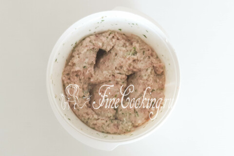 Однородный мясной фарш с зеленью и луком в миске