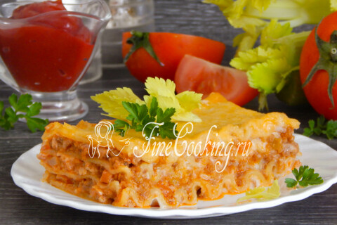Готовая лазанья нарезана порционными кусочками на тарелке