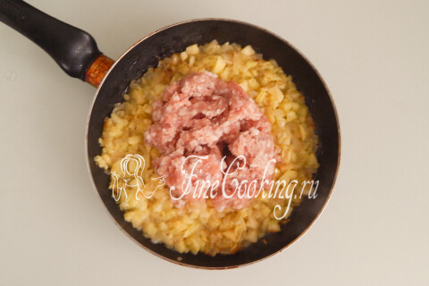 Мясной фарш с луком и кабачками на сковороде, разбитый лопаткой на кусочки.