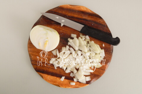 Репчатый лук, нарезанный мелким кубиком, на разделочной доске.