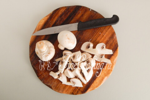Свежие шампиньоны, нарезанные произвольными кусочками, на доске.
