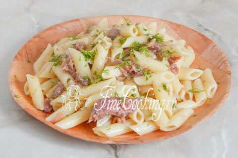 Макароны по-флотски, поданные в тарелке с измельчённой зеленью.
