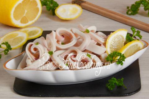 Маринованные кальмары на тарелке, украшенные ломтиками лимона