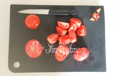 Помидоры, нарезанные дольками, с вырезанным местом крепления плодоножки на разделочной доске.