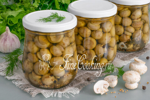 Маринованные шампиньоны в стеклянной банке поданы как холодная закуска.