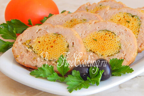 Мясной рулет с макаронами на тарелке со свежими овощами и зеленью