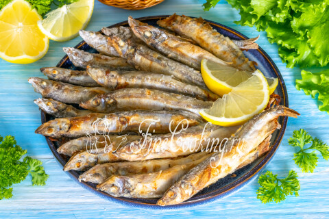 Запечённая мойва с румяной хрустящей корочкой на тарелке, подача горячей.